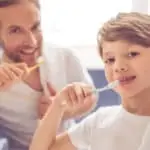 father and son brushing teeth